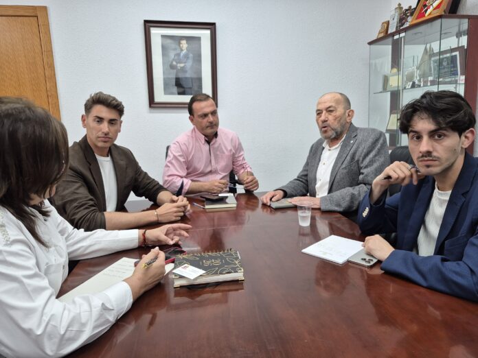 Five professionals seated around a polished conference table in a meeting room, with notebooks and a smartphone visible on the table.