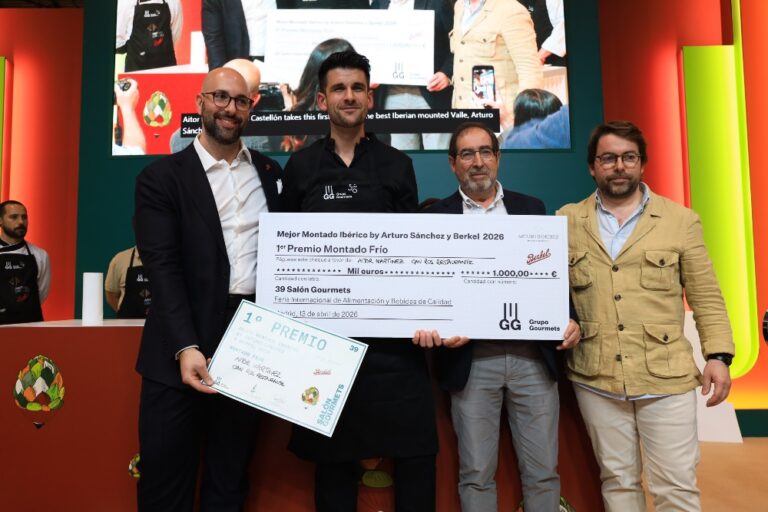 Group of four men on stage holding a large ceremonial check and a certificate during an awards event.