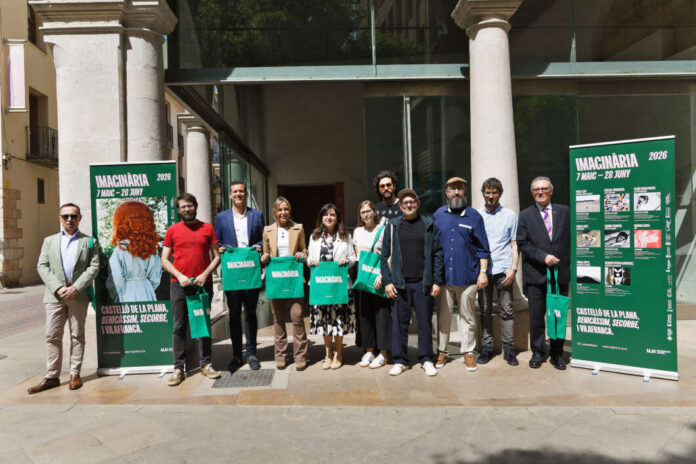 Group of people posing outside a building with two green Imaginària 2026 posters, holding green tote bags.