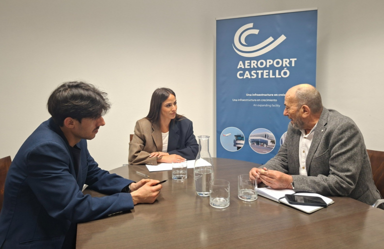Three professionals sit at a conference table in a discussion, with an Aeroport Castelló banner in the background.