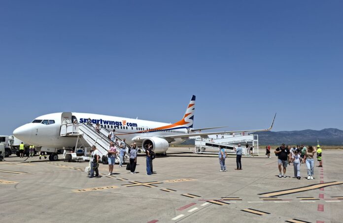 Passenger boarding a Smartwings airliner on the sunny tarmac with stairs attached to the door, blue sky above.