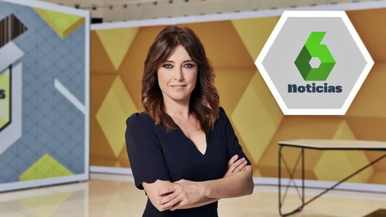 News anchor wearing a navy dress stands in a yellow geometric TV studio with the Noticias logo visible in the background.