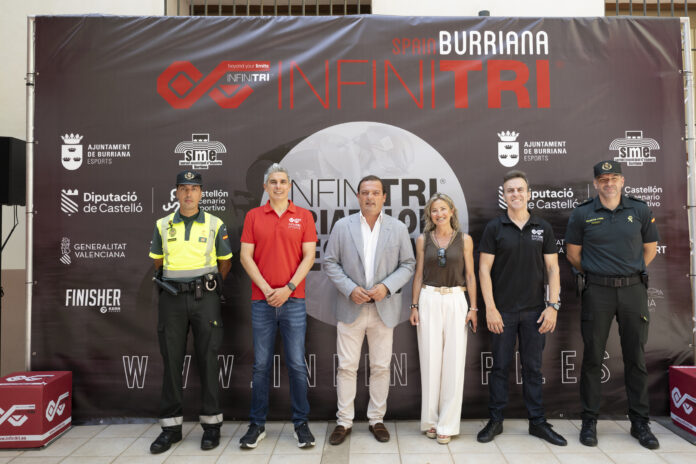 Six adults pose in front of a large dark event banner featuring INFINITRI branding and sponsor logos.