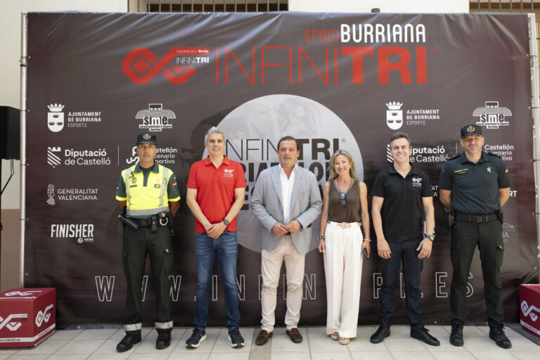 Six adults pose in front of a large dark event banner featuring INFINITRI branding and sponsor logos.