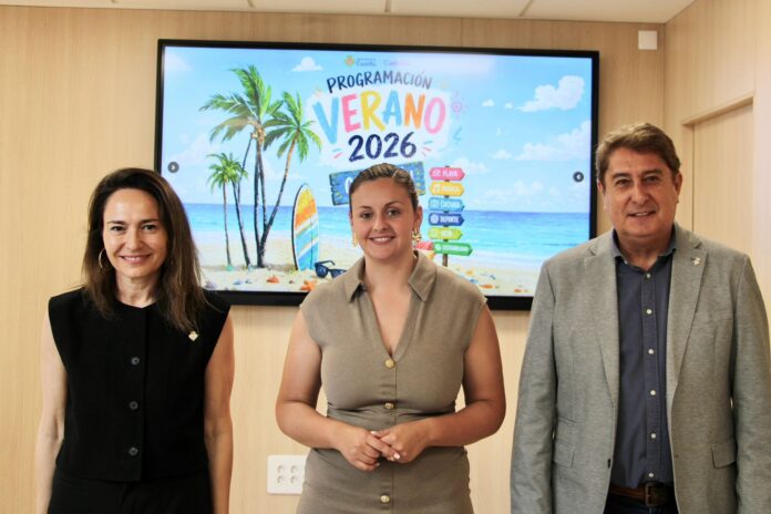 Three adults pose in front of a tropical beach-themed presentation on a screen behind them.