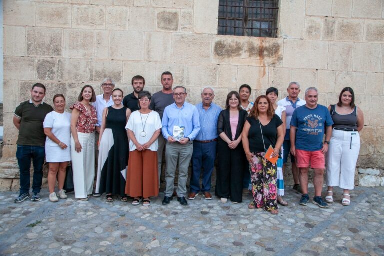 A diverse group of adults posing for a group photo in front of a beige stone wall.