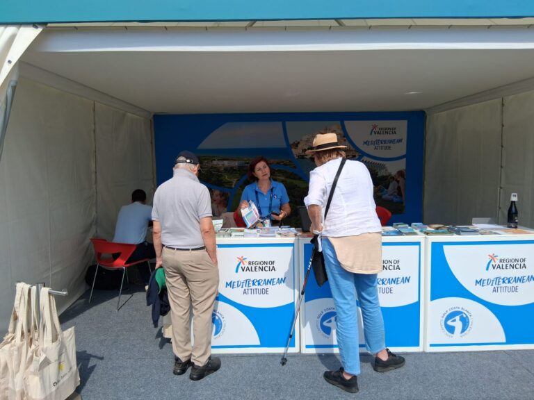 Region of Valencia information booth inside a tent; staff distributes brochures to visitors.