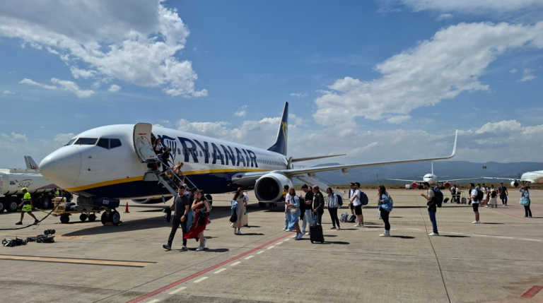 Ryanair plane at the gate with passengers walking off the stairs onto the tarmac.